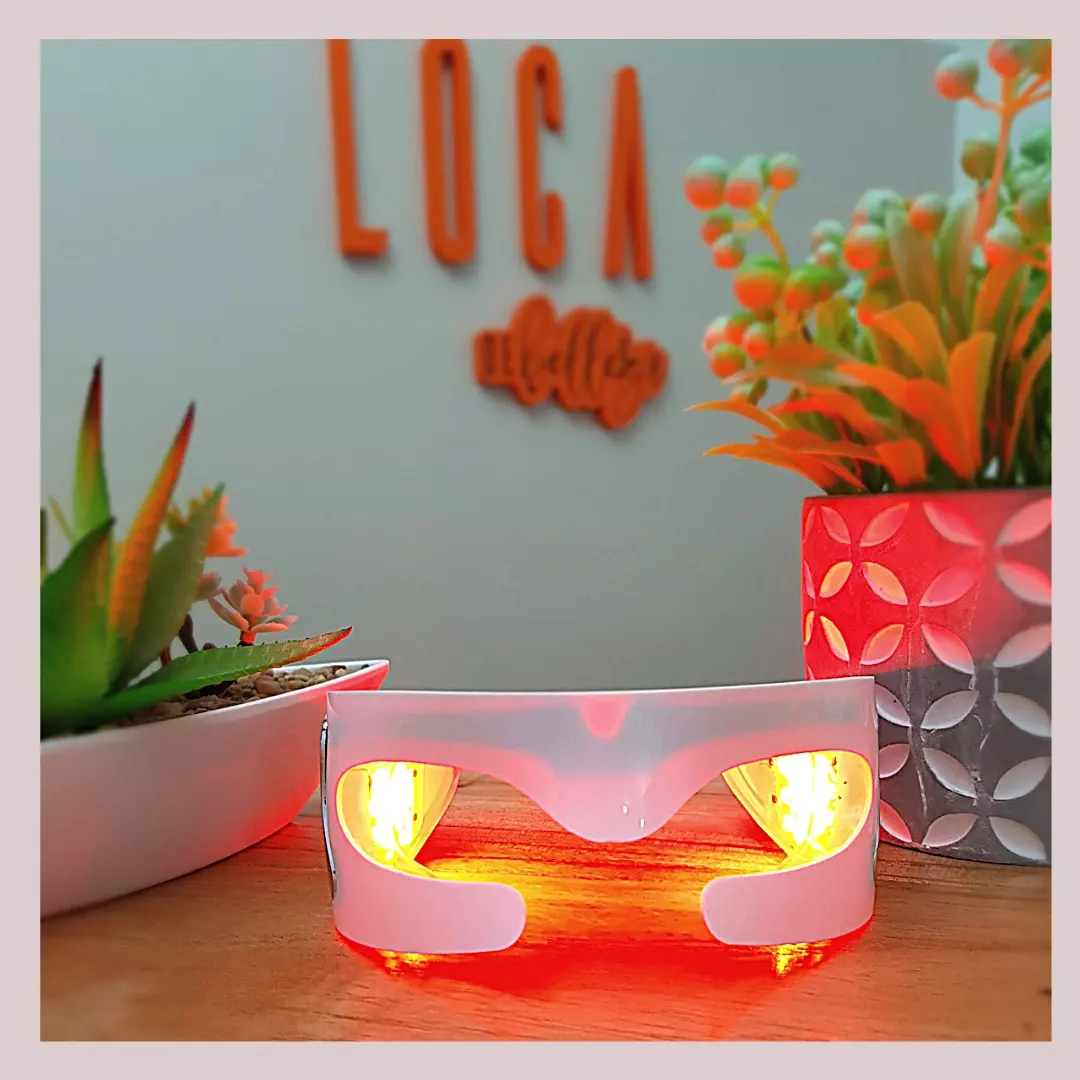 La máscara LED Therapy encendida sobre la mesa, delante de las letras naranjas LOCA de nuestra pared